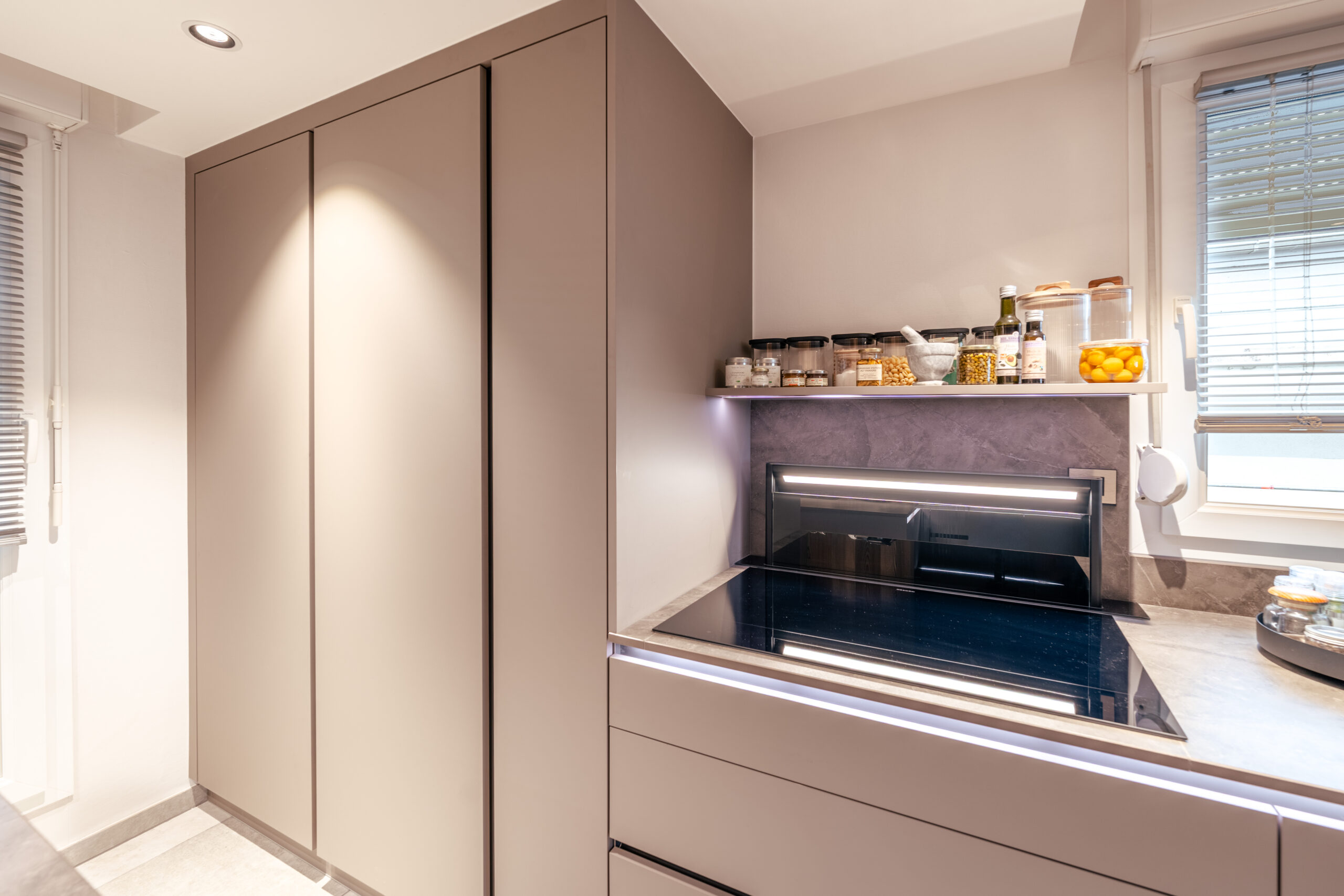 Colonne de rangement et zone de cuisson intégrées entre deux ouvertures dans une cuisine Erhart & Fils